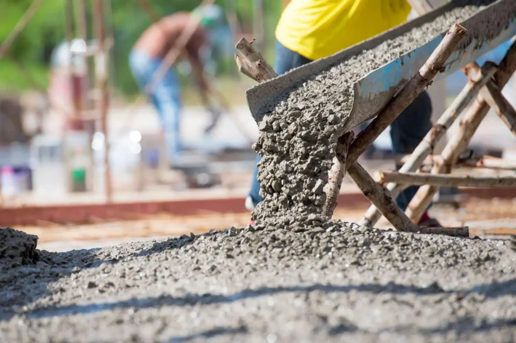 Skilled concrete contractors in Dallas TX mixing and pouring fresh concrete mix at construction site using professional-grade equipment.