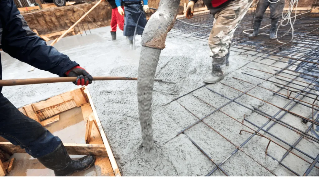 Experienced concrete contractors in Dallas TX pouring fresh concrete onto reinforced foundation with rebar grid during new construction.